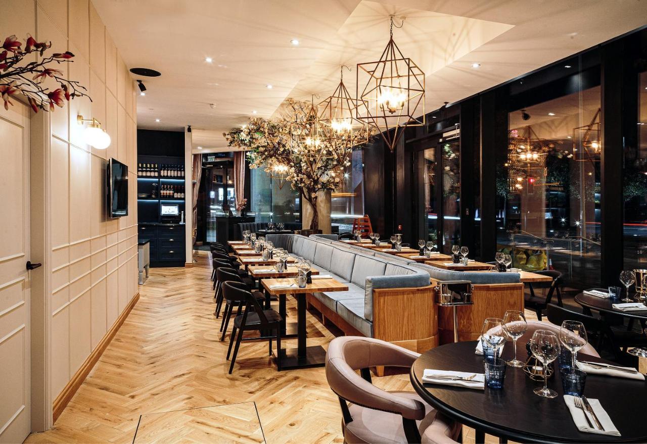 Citysuites Aparthotel Salford  Ngoại thất bức ảnh The photo depicts an elegantly designed restaurant interior. The space features a mix of seating options with wooden tables and grey upholstered chairs. There are large windows allowing natural light, and the decor includes stylish pendant lights and