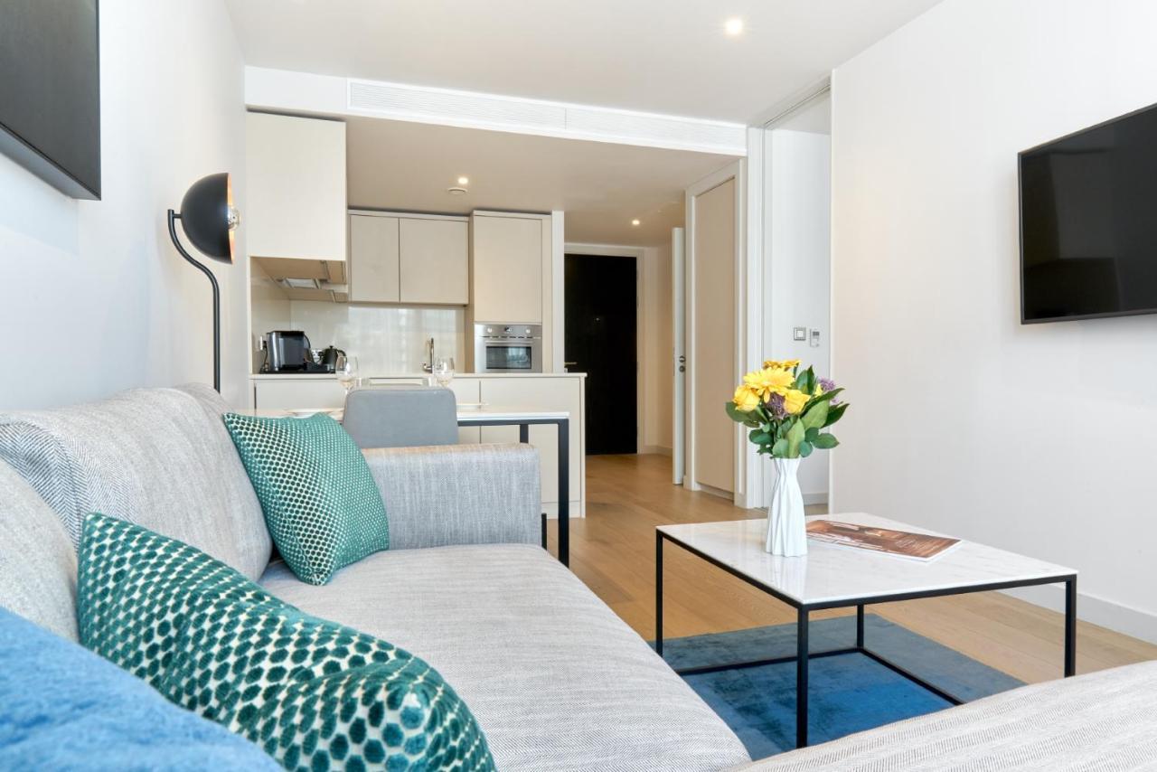 Citysuites Aparthotel Salford  Ngoại thất bức ảnh The photo shows a modern and stylish living space. On the left, there is a light gray couch adorned with decorative pillows, including a blue one and a green patterned one. In front of the couch, there is a sleek coffee table with a vase of fresh flo