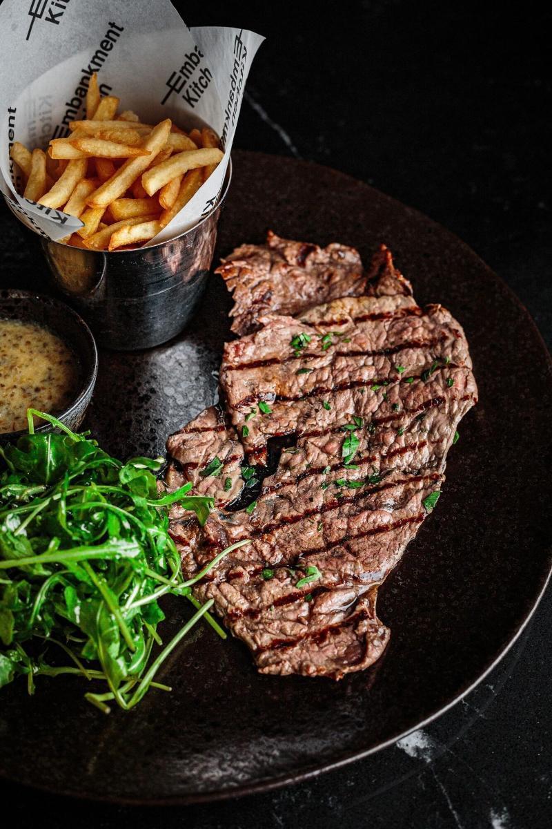 Citysuites Aparthotel Salford  Ngoại thất bức ảnh The photo shows a gourmet dish featuring a grilled portion of steak that is garnished with chopped parsley. It is served alongside a small bowl of mustard sauce and a portion of golden French fries in a metal cup. Additionally, there is a fresh side 