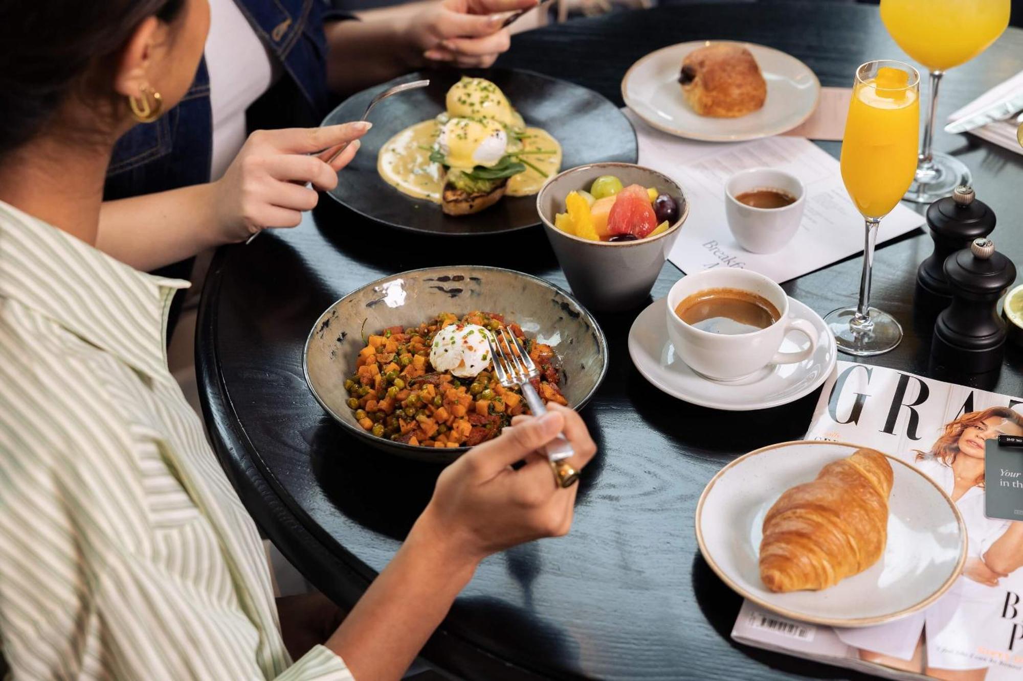 Citysuites Aparthotel Salford  Ngoại thất bức ảnh The photo portrays a dining setting with several dishes and drinks. In the foreground, a person is holding a fork, poised to eat from a bowl filled with a colorful mixture that appears to include vegetables and garnished with a dollop of cream. 

Nea