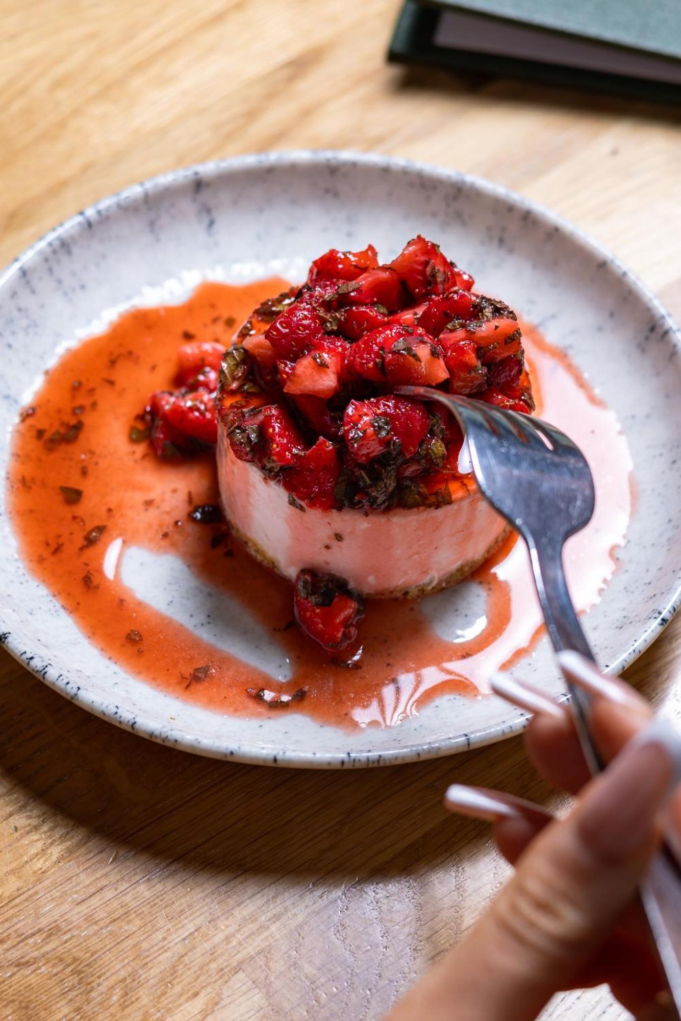 Citysuites Aparthotel Salford  Ngoại thất bức ảnh The photo showcases a dessert that features a round, creamy base topped with a generous portion of strawberries. The strawberries appear to be fresh and are drizzled in a reddish syrup, which may also include some chocolate or other flavors. A fork i