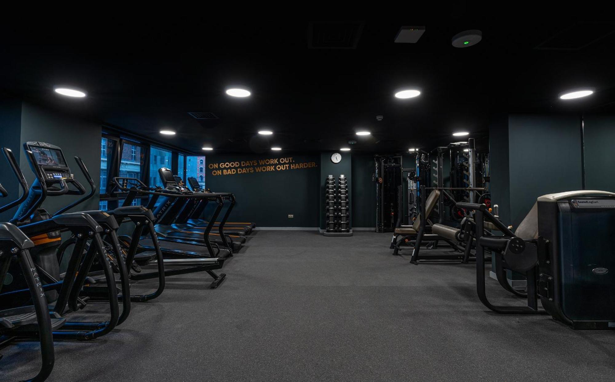 Citysuites Aparthotel Salford  Ngoại thất bức ảnh The photo shows an interior view of a gym. There are several fitness equipment pieces arranged in the space, including treadmills and weight machines. The gym features dark-colored walls and flooring, contributing to a sleek, modern look. Natural lig