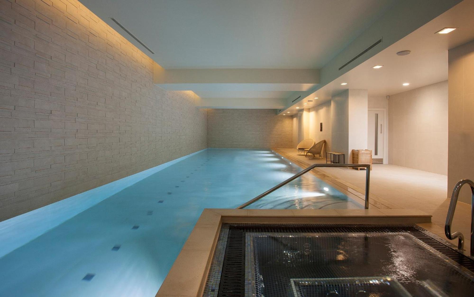 Citysuites Aparthotel Salford  Ngoại thất bức ảnh The photo shows a serene indoor swimming pool area. The pool is rectangular and features calm, clear water. On one side, there are steps leading into the pool, and the surrounding walls are made of light-colored bricks, contributing to a tranquil amb