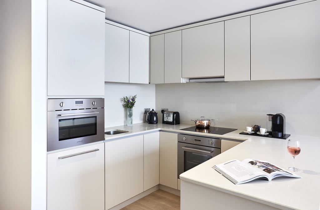 Citysuites Aparthotel Salford  Ngoại thất bức ảnh The photo shows a modern kitchen with a sleek and minimalist design. The cabinetry is predominantly white, with smooth, flat surfaces. 

There is an oven built into the cabinetry, along with a stovetop. On the countertop, you can see a coffee maker, 