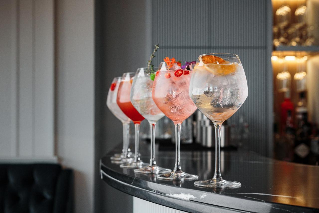 Citysuites Aparthotel Salford  Ngoại thất bức ảnh The photo shows a selection of five elegant cocktails arranged neatly on a bar counter. Each cocktail is served in a large, round glass and features different colors and garnishes. 

- The first cocktail on the left appears to have a red hue with gar